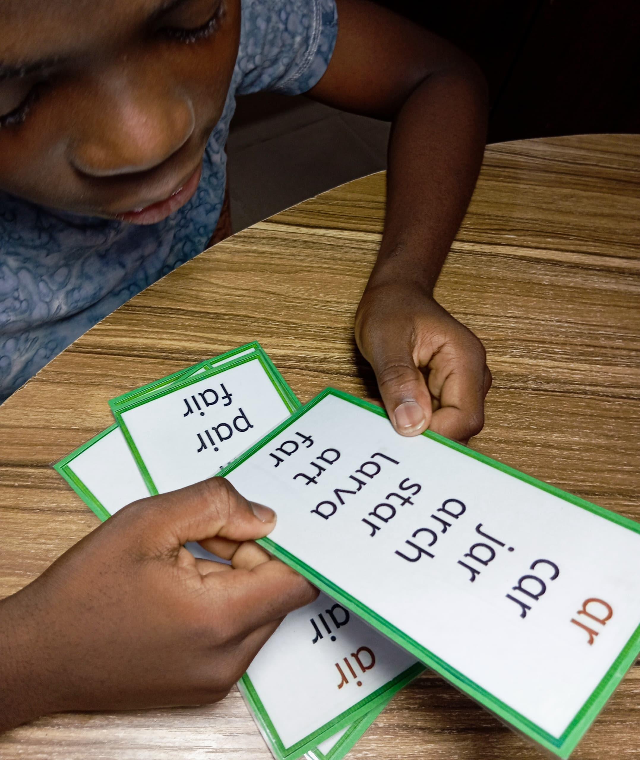 A young reader working through phonics word cards